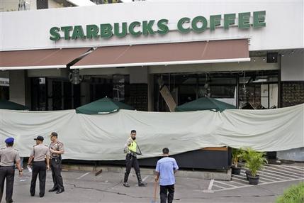 Police and officials gather in the parking lot outside the damaged Starbucks cafe where Thursday's attack occurred in Jakarta Indonesia